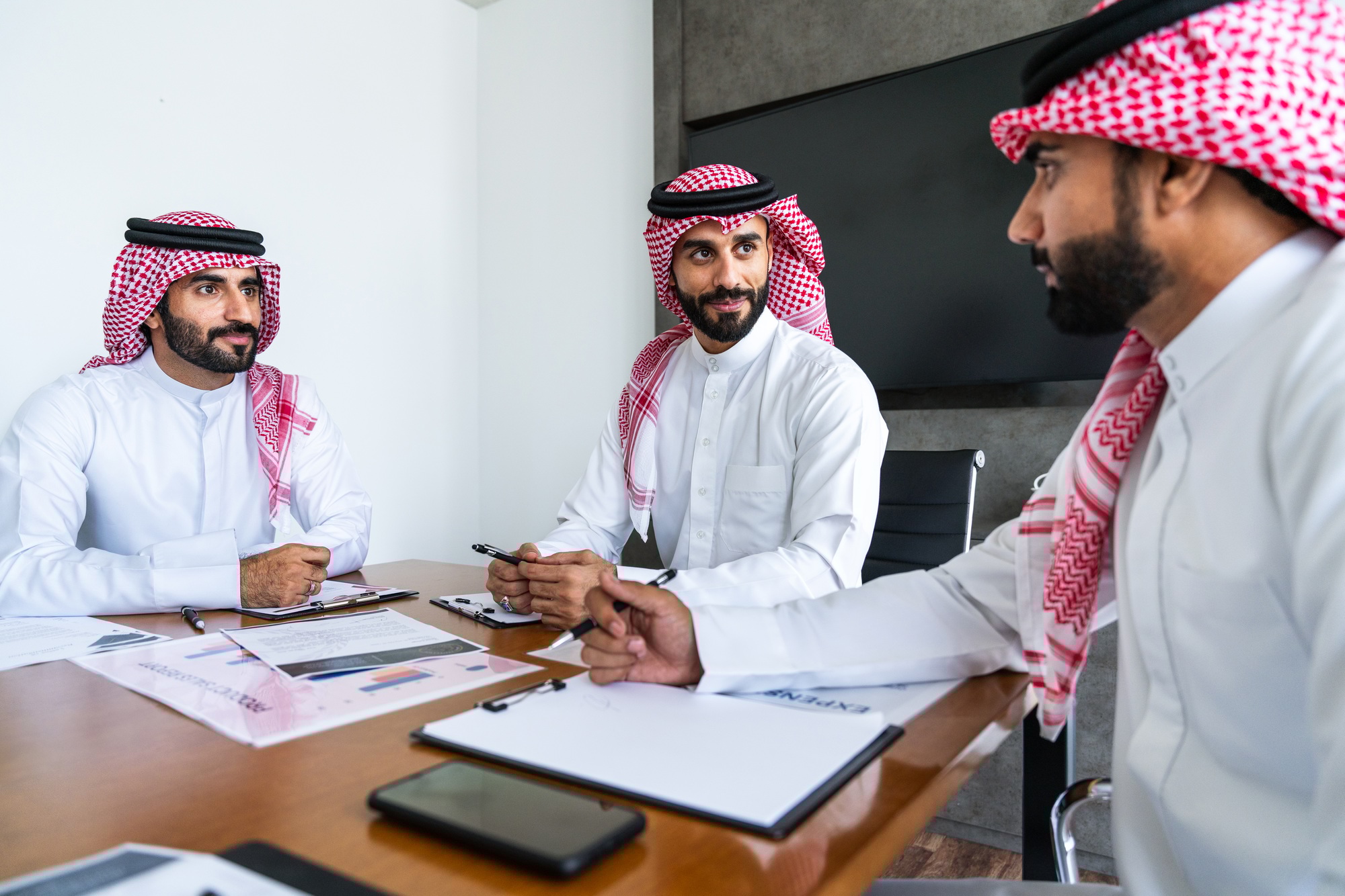 Arab businessmen wearing saudi kandura meeting in office for business deal